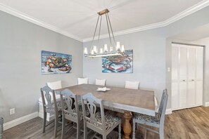 Ein Esszimmer mit Holztisch, sechs Stühlen, einer Chandelierleuchtre und zwei Bildern an den Wänden.