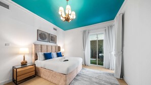 A bedroom with a bed, bedside tables, a chandelier, and a view of the outdoors. - Free Housekeeping Visits During Your Stay - Stayshort - Comfortable 1 Bedroom in Marina With Balcony (Dubai)