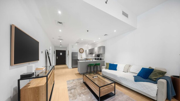 A modern living room with a sofa, coffee table, and a TV on a stand. - Free Housekeeping Visits During Your Stay - Stayshort - Comfortable 1 Bedroom in Marina With Balcony (Dubai)