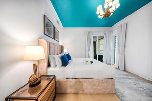 Ein modernes Hotelzimmer mit einem Bett, einem Nachttisch mit Lampe und Blick durch eine Glastür nach draußen.