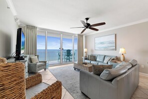 A spacious living room with a balcony, a ceiling fan, a television, and a sofa set. - San Carlos 1409 by Liquid Life (Gulf Shores)