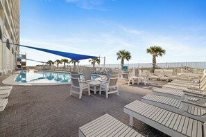 A pool area with lounge chairs and a blue canopy. - San Carlos 1409 by Liquid Life (Gulf Shores)