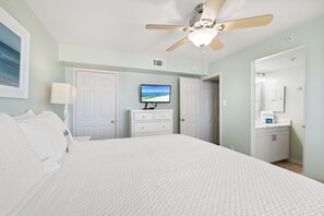 Ein Hotelzimmer mit Bett, Fernseher, Deckenventilator und Badezimmer.