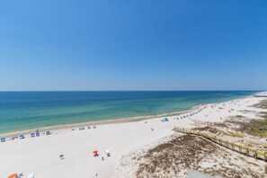 A beach with a sandy shore, umbrellas, and a clear blue sky. - Royal Palms 1008 by Liquid Life (Gulf Shores)