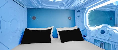 Una habitación futurista con cama, paneles de control y una ventana.