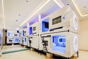 A row of bunk beds with built-in lighting, in a clean and modern room with a tiled floor.