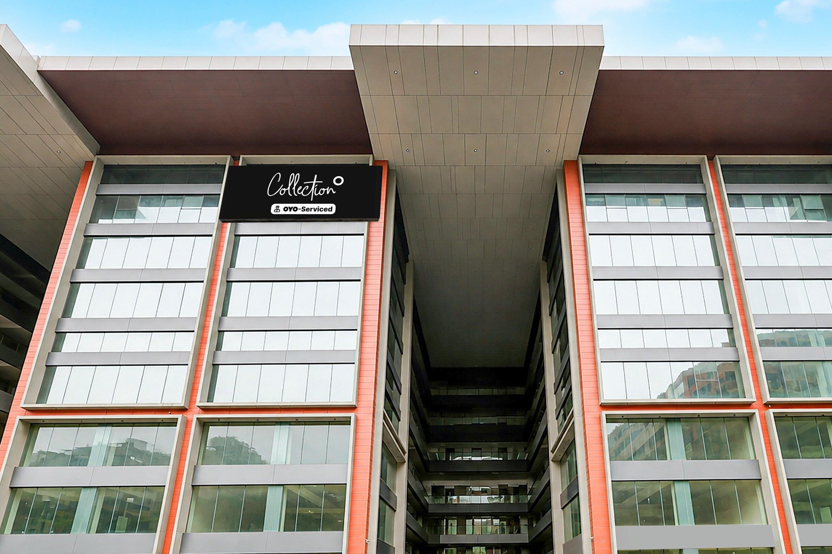 A building with a sign that reads 'Collection OYO-Serviced' and a modern architectural design with large windows and a central atrium.