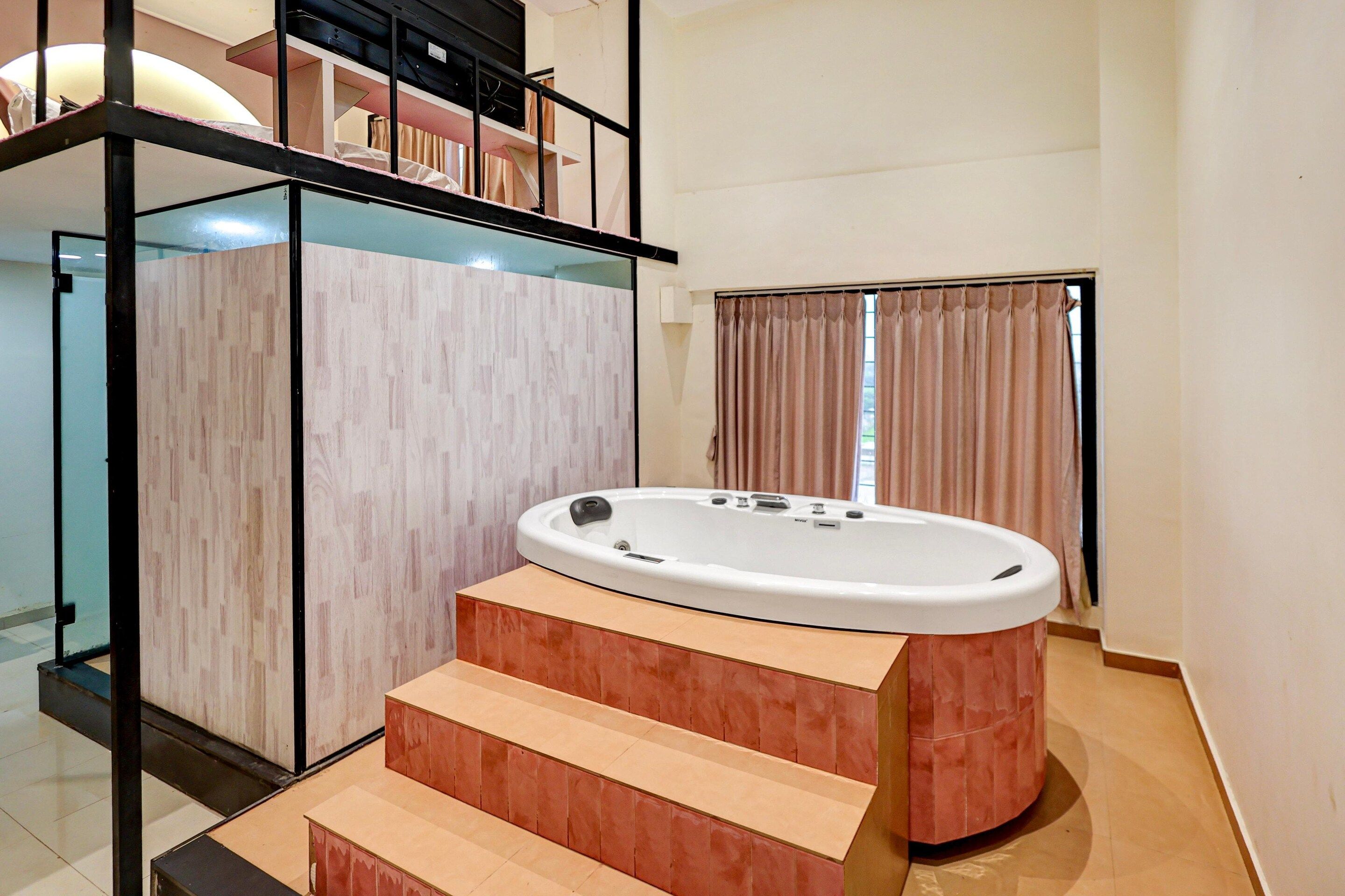 A modern bathroom with a freestanding bathtub, a glass-enclosed shower area, and a staircase leading to an upper level.
