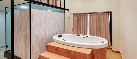 A modern bathroom with a freestanding bathtub, a glass-enclosed shower area, and a staircase leading to an upper level.