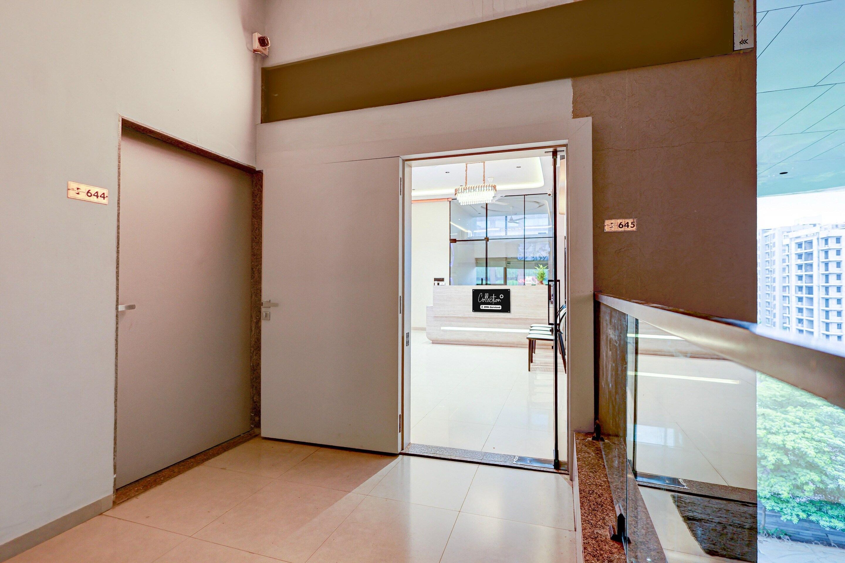 A hotel reception area with a glass door, a reception desk, and a view of the outside.