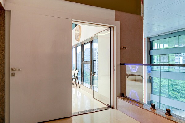 A hotel room with a large sliding glass door leading to a balcony with a city view.