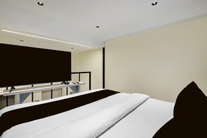 A modern hotel room with a bed, a desk, and a television.