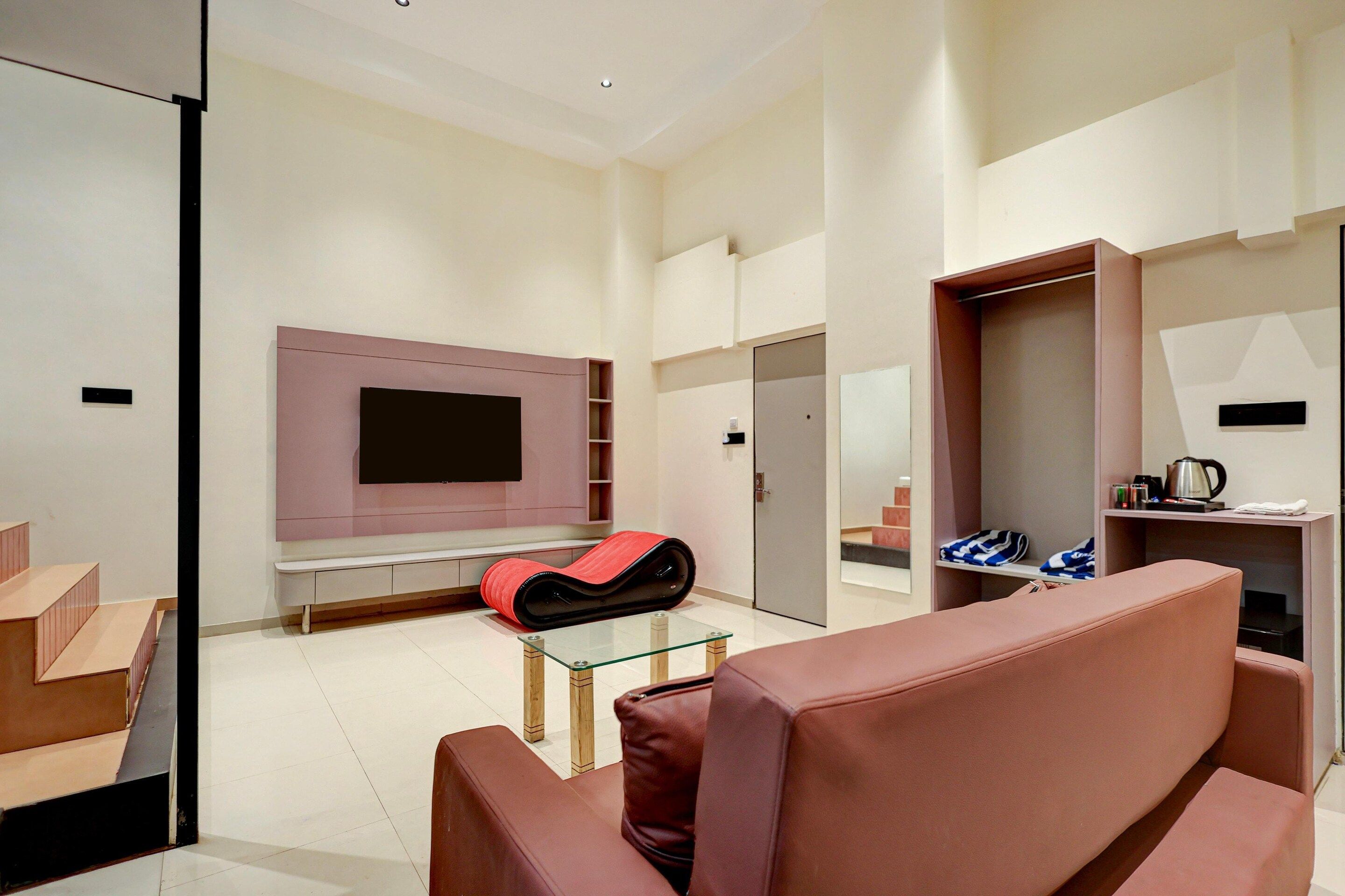 A modern living room with a flat-screen TV mounted on the wall, a glass coffee table, and a red sofa.