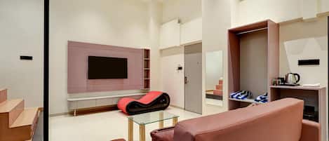 A modern living room with a flat-screen TV mounted on the wall, a glass coffee table, and a red sofa.