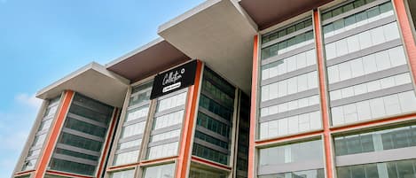 A modern building with a flat roof, large windows, and a sign indicating it is a serviced apartment.