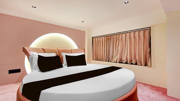 Une chambre moderne avec un grand lit, une tête de lit, une fenêtre avec des rideaux et un luminaire fixé au mur.