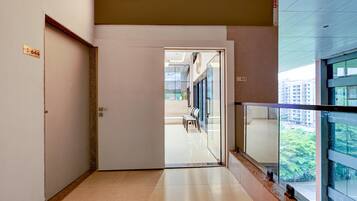 A hallway with a door labeled '644' leading to a waiting area with chairs and a view of buildings outside.