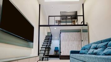 A modern interior with a staircase leading to a loft area, a sofa, and a desk.