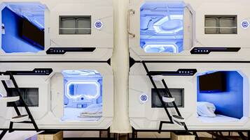 A hotel room with a bed, bedside tables, and a control panel.