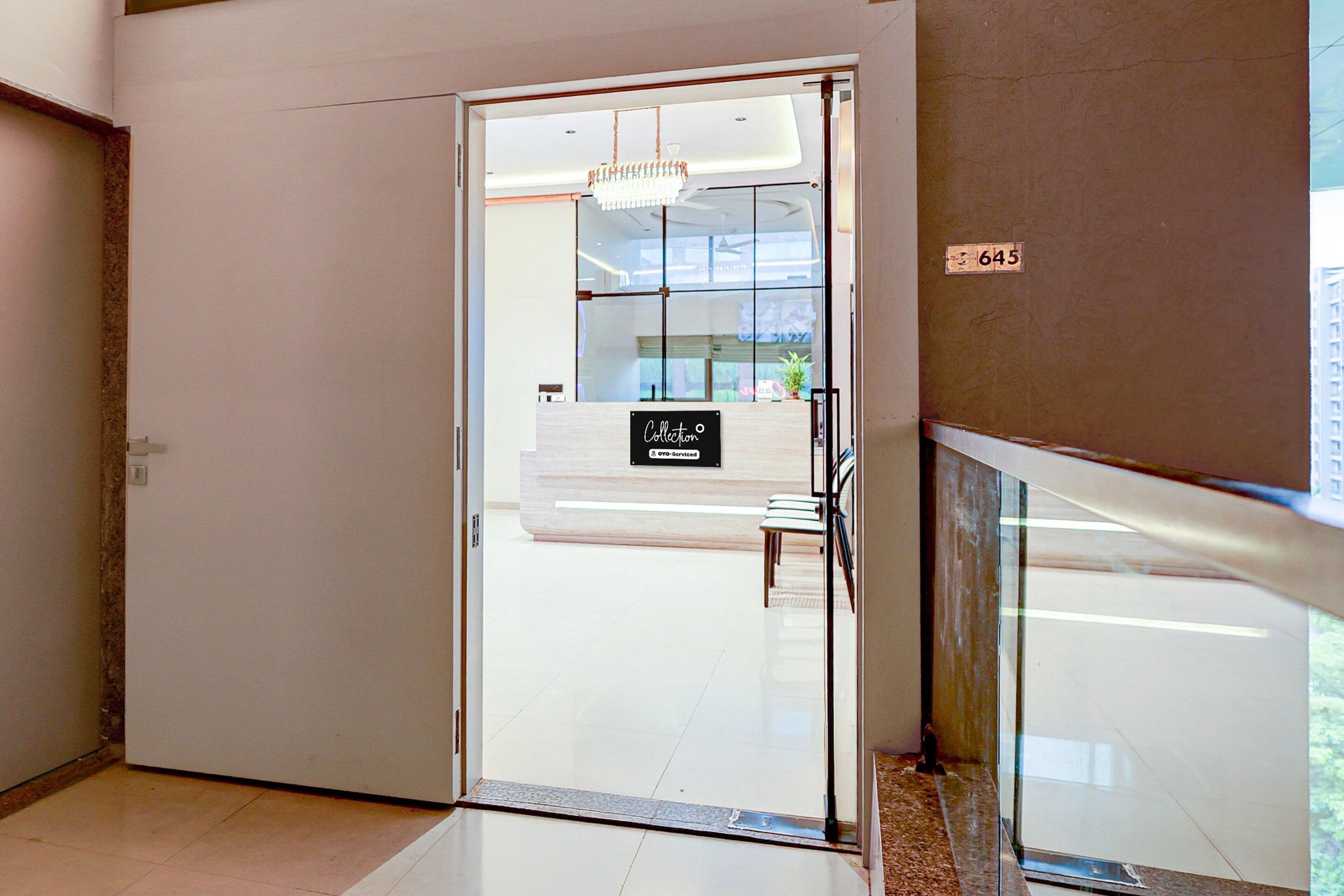 A modern hotel lobby with a glass door leading to a reception area.