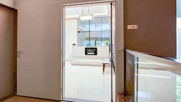 A modern hotel lobby with a glass door leading to a reception area.