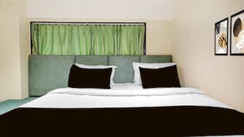 A bedroom with a bed, green curtains, and two framed artworks on the wall.