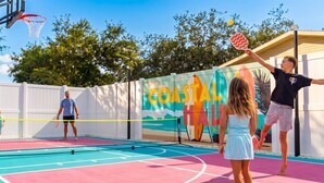 En utomhusbasketplan med en färgstark väggmålning i bakgrunden, en basketkorg och ett nät.