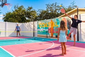 An outdoor basketball court with a colorful mural in the background, a basketball hoop, and a net. - Resort-style 5BR/3BA home, 8 min to Anna Maria Island. Private heated pool, splash pad, home theater, arcade, pickleball court, sauna & hot tub — sleeps 18 with a boat-themed bunk room kids love. Everything your group needs, right at home. (Bradenton)