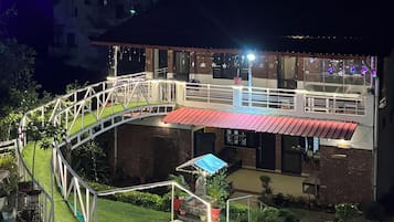 Un edificio con una zona esterna coperta, un vialetto e piante.