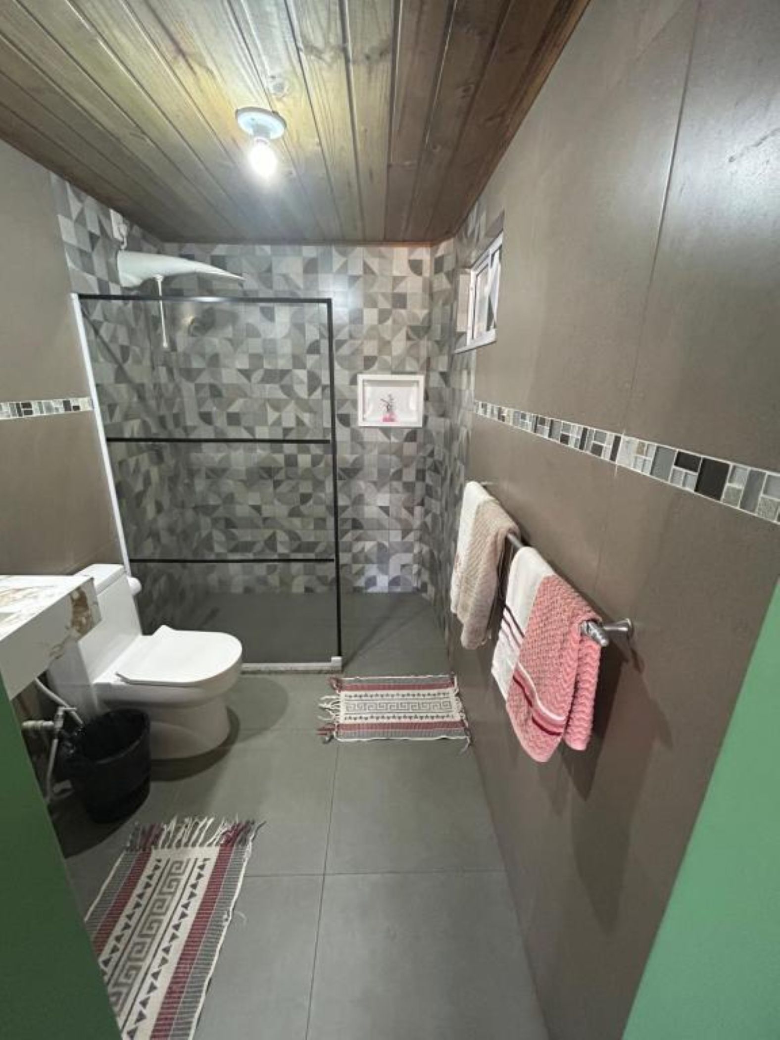 Een compacte badkamer met toilet, douche en wastafel.