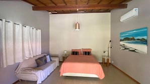 A bedroom with a bed, a sofa, a lamp, an air conditioner, and a painting on the wall. - Pousada destino  (Entre rios)