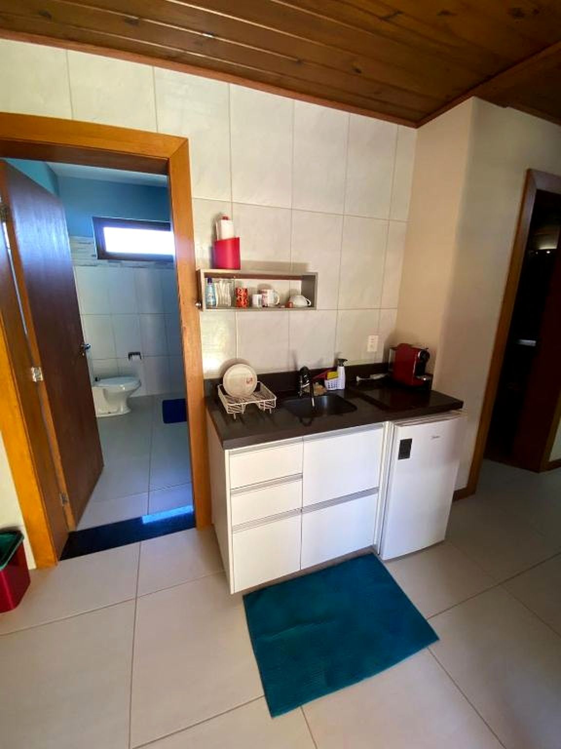 A compact kitchen with a sink, a refrigerator, and a countertop with various items.