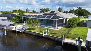 A modern house with a covered patio, a swimming pool, and a boat dock. - Villa Dolphin – Prime Location, Southern Exposure, Pool & Gulf Access (Cape Coral)