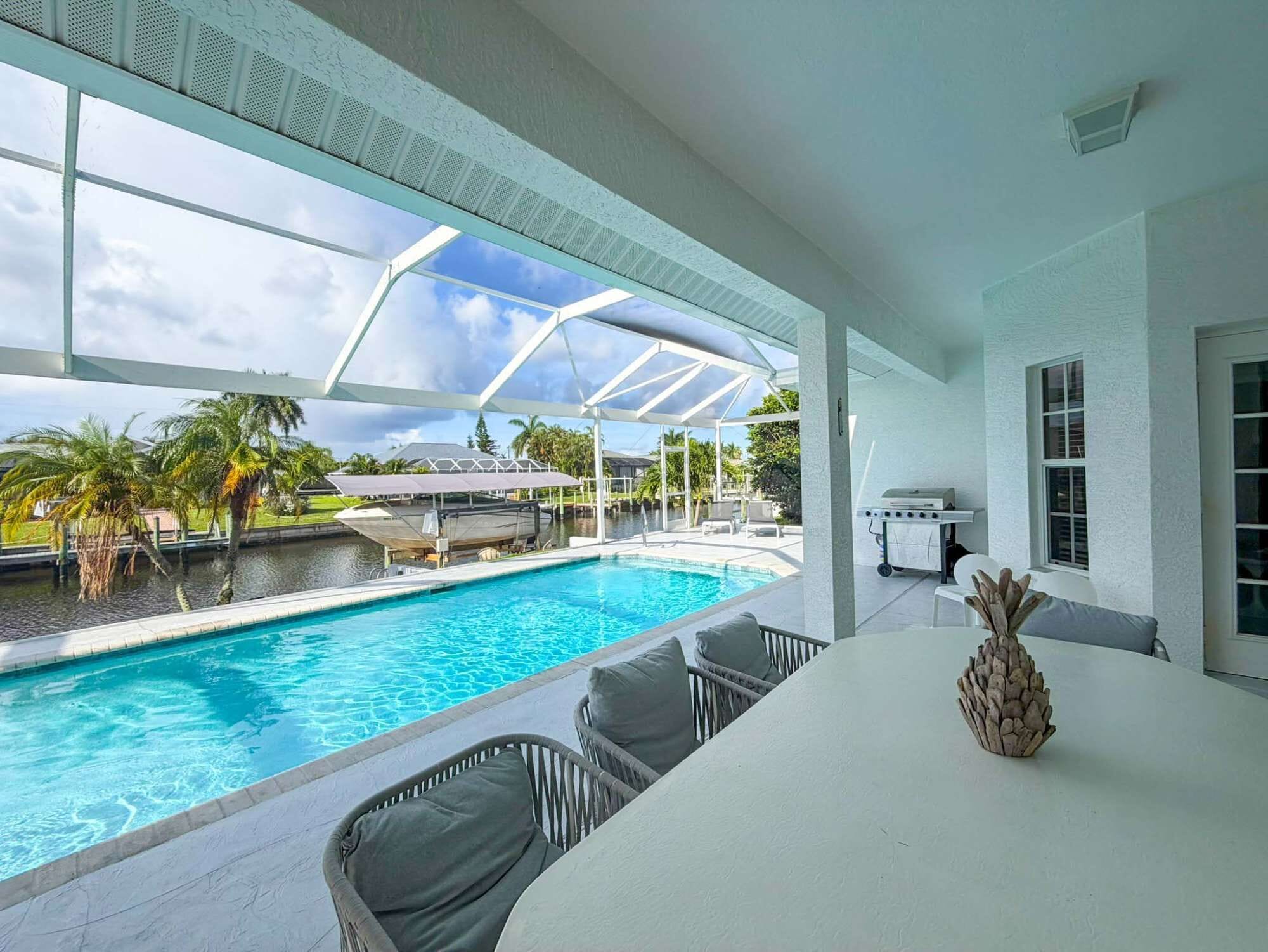 A poolside area with a view of the pool, outdoor furniture, and a grill.