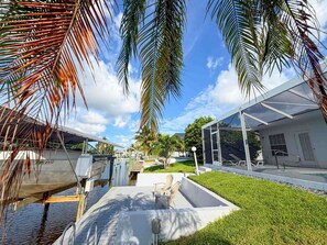 Un bâtiment moderne doté d’une façade en verre, d’une piscine et de palmiers.