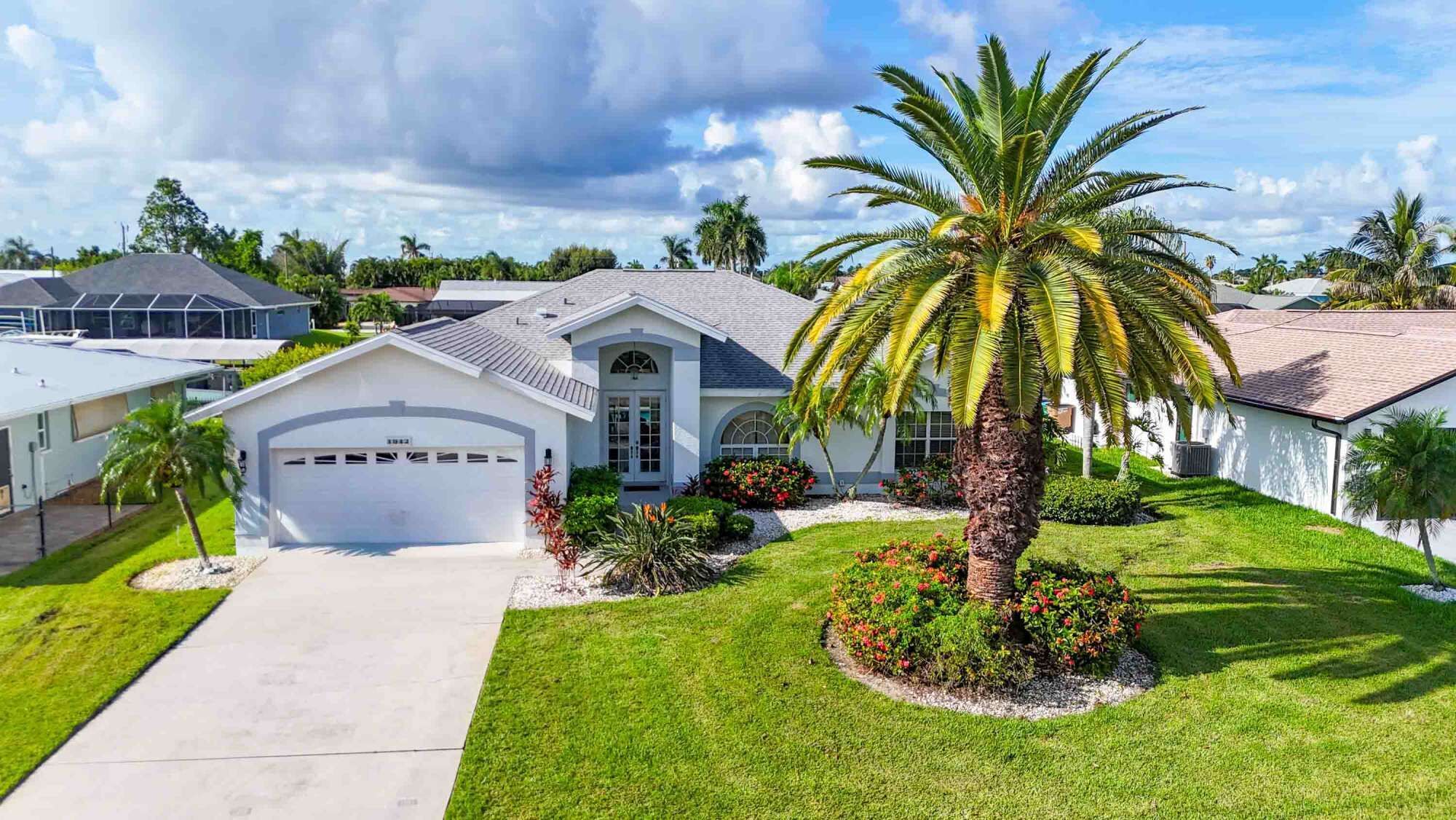 A residential house with a garage, a well-maintained lawn, and a palm tree.