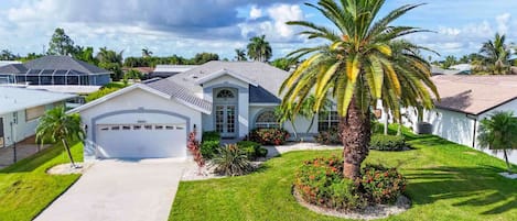 A residential house with a garage, a well-maintained lawn, and a palm tree.