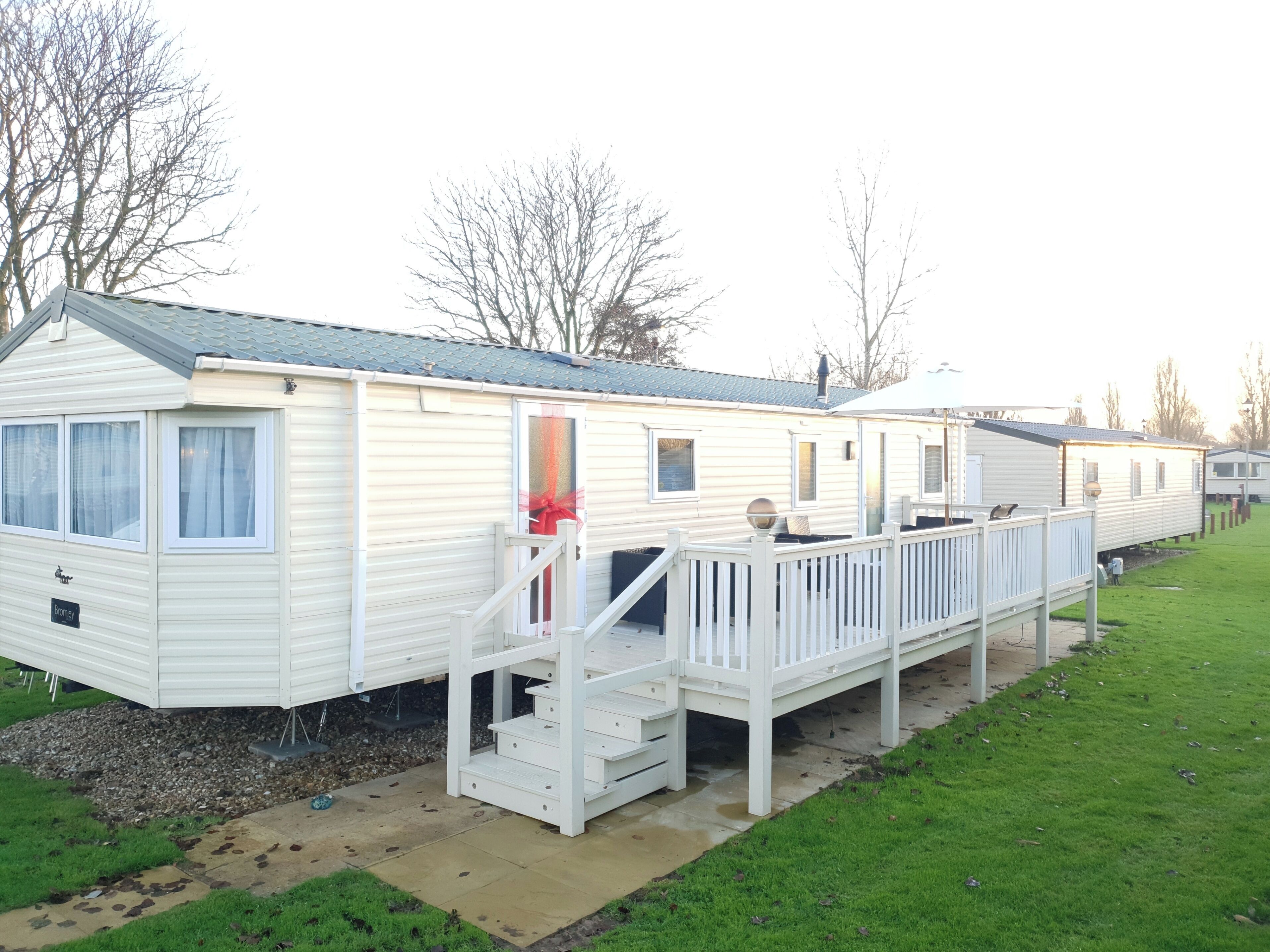 A row of mobile homes with a deck and stairs leading to the entrance.