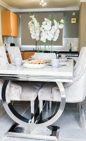 A dining area with a white table, chairs, and a decorative centerpiece. - House Sleeps 7 With Parking (Northampton)