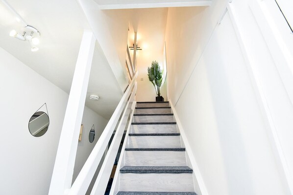 A staircase with a modern design, white walls, and a potted plant at the top. - House Sleeps 7 With Parking (Northampton)