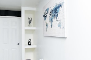 A room with a white door, a world map on the wall, and a shelf with decorative items.