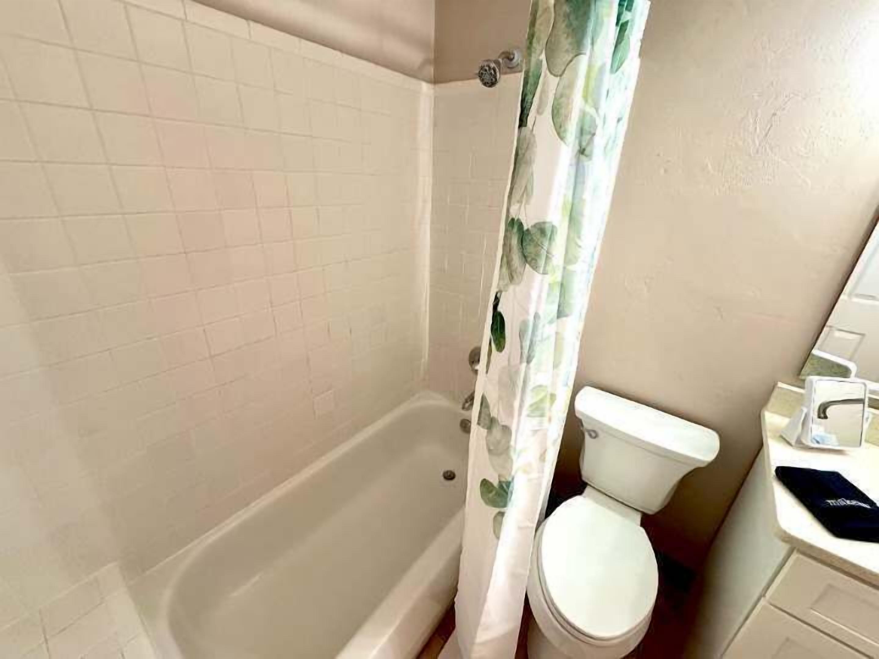 A bathroom with a bathtub, toilet, and a shower curtain.