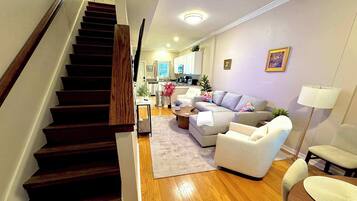 A staircase leading to a living area with a sofa, armchairs, and a coffee table.