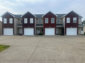 A row of townhouses with attached garages, a concrete driveway, and a clear sky. - Stylish 3BR Townhouse (Radcliff)