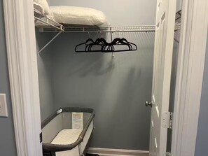 Ein Zimmer mit Etagenbett, einem kleinen Babybett und einem Kleiderständer.