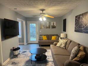 A living room with a sofa, coffee table, and artwork on the walls. - Stylish 3BR Townhouse (Radcliff)