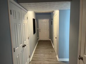 A hallway with white doors, a wooden floor, and a light blue wall. - Stylish 3BR Townhouse (Radcliff)