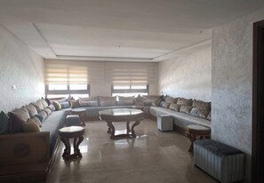 Ein geräumiges Wohnzimmer mit einer großen Eckcouch, einem runden Couchtisch und einem kleinen Beistelltisch.