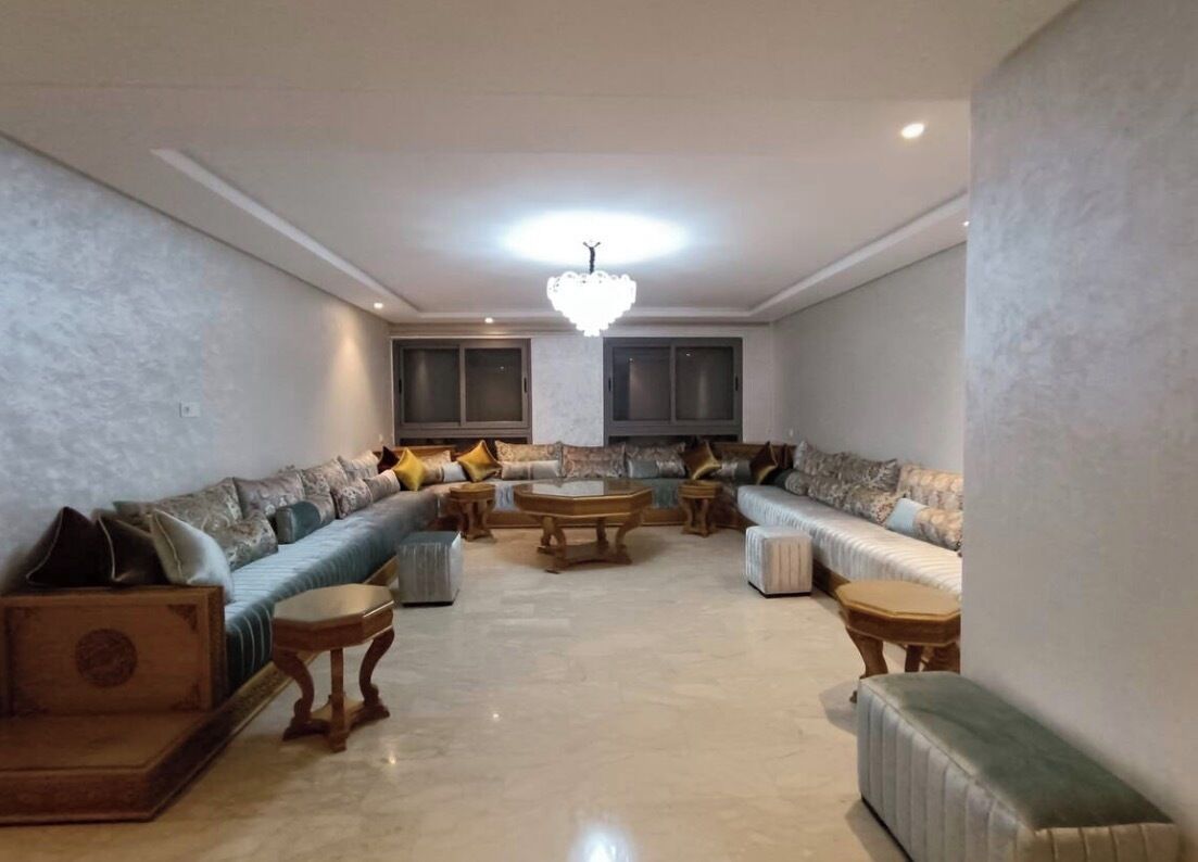 A living room with a sectional sofa, a coffee table, and a chandelier.