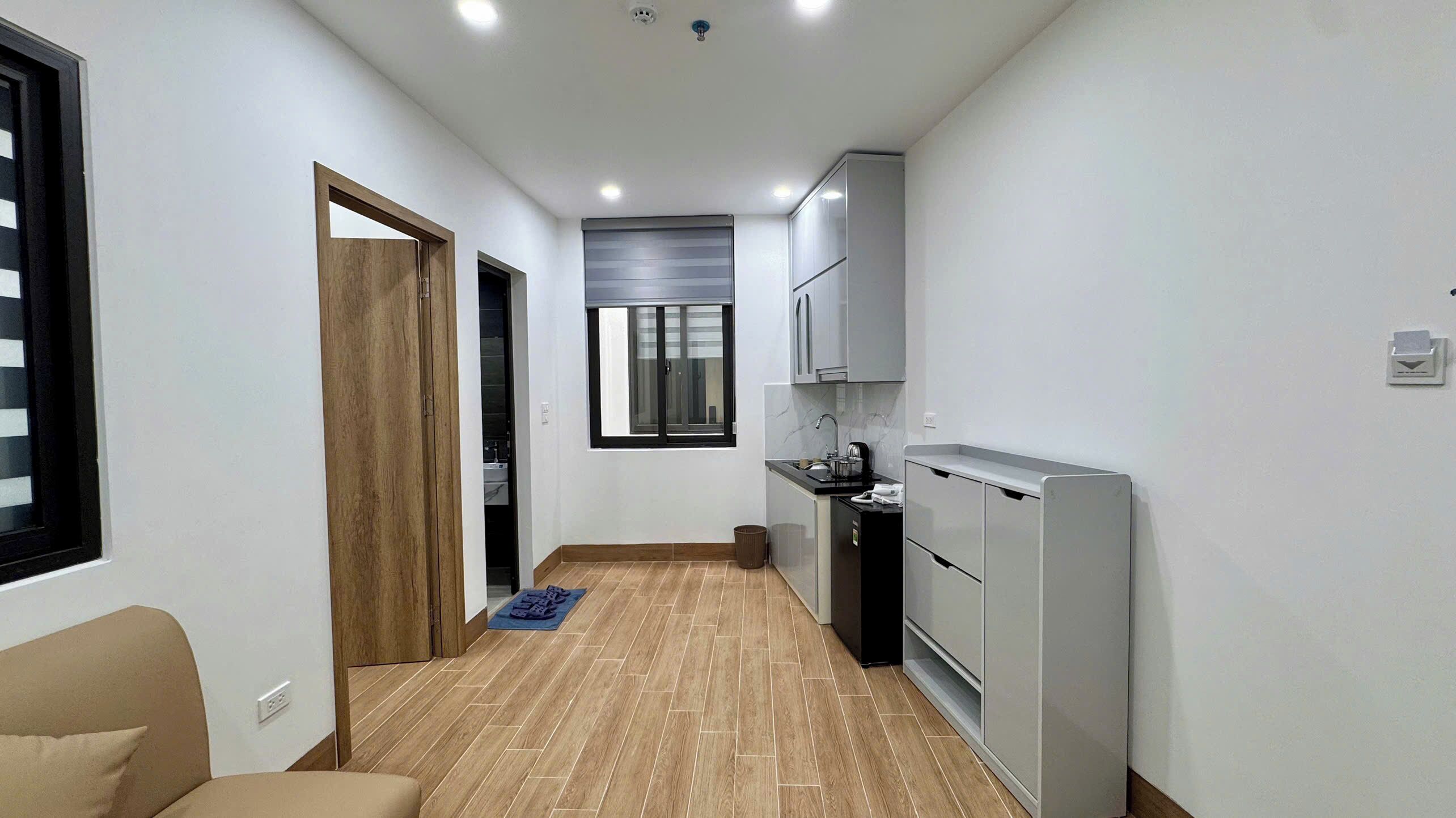 A narrow hallway leading to a kitchen with a refrigerator, a sink, and cabinets.